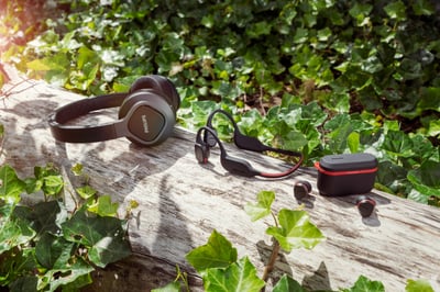 Philips sportkoptelefoons en oordopjes buiten tentoongesteld op een boomstam, omringd door groen