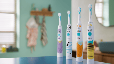 Four colourful Philips Sonicare for Kids electric toothbrushes are on display in a bathroom.