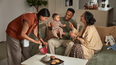 A man and woman play with a baby while another woman, wearing a Philips hands-free breast pump, looks in her bag.