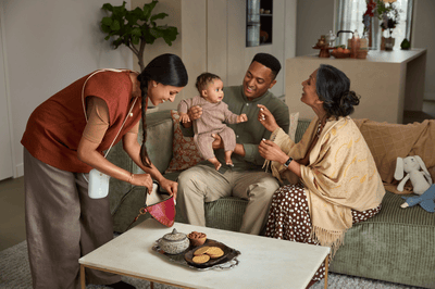 A man and woman play with a baby while another woman, wearing a Philips hands-free breast pump, looks in her bag.