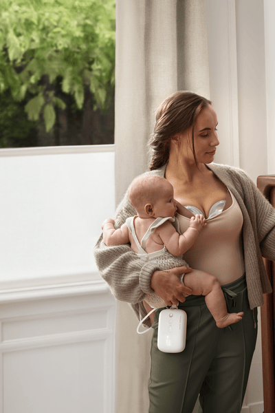 Mother pumping breast milk hands-free while multi-tasking