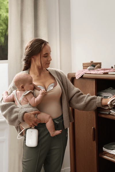 Mother pumping breast milk hands-free while multi-tasking