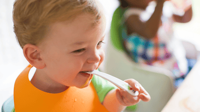 Copil mic zâmbește în timpul mesei