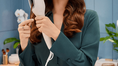 Žena si upravuje vlasy kulmou