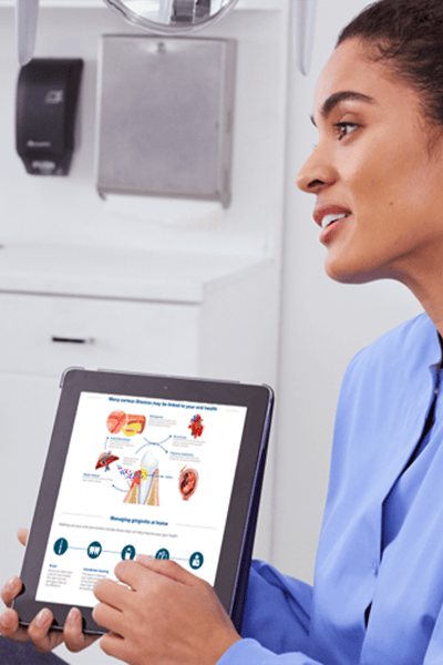 A dental professional holding the chairside guide converses with patient.
