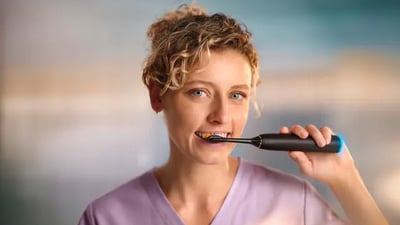 A young dental professional brushes her teeth with a Philips Next-Generation DiamondClean toothbrush.