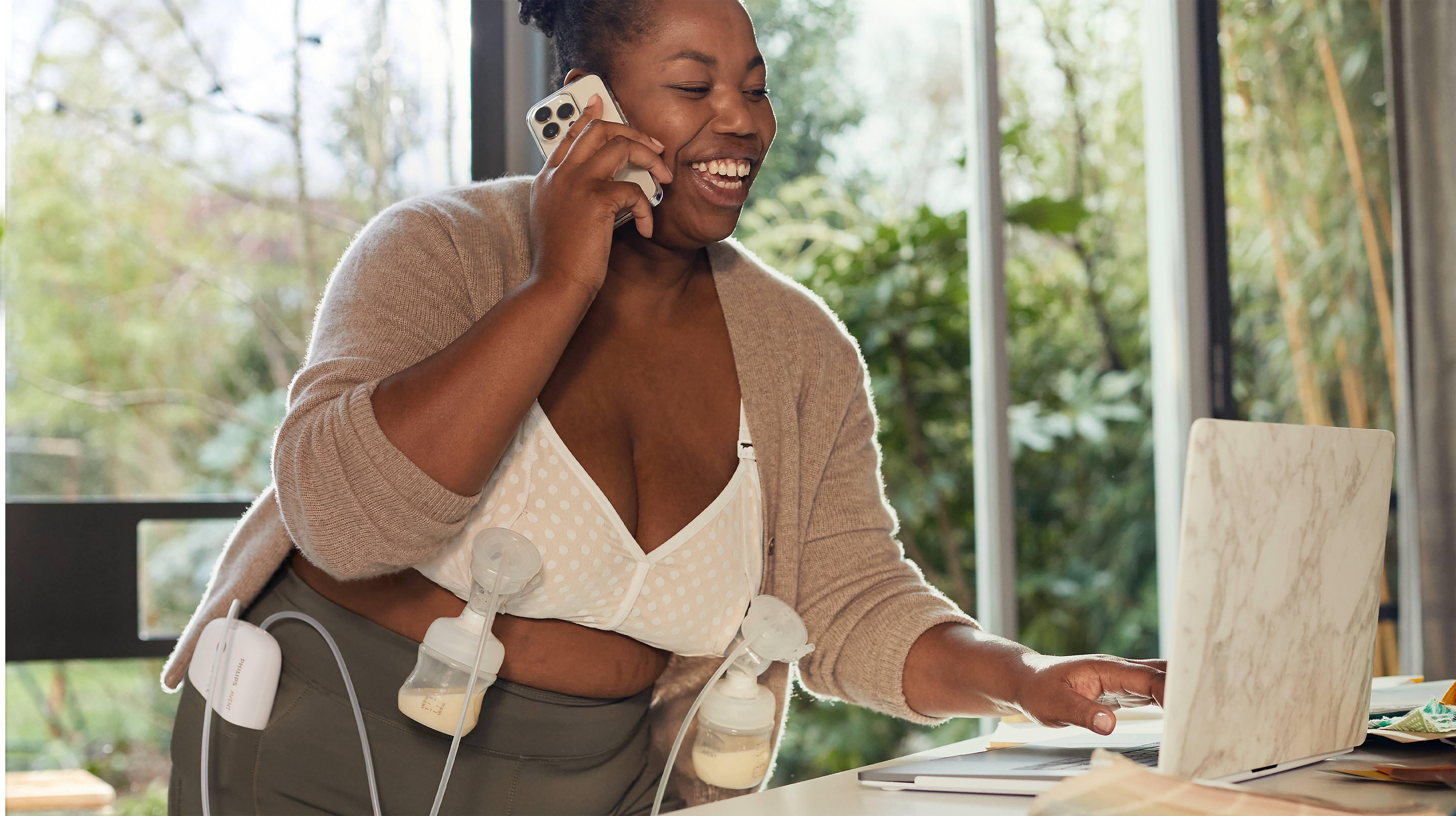 Mum talking on the phone while wearing breast pumps