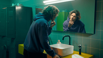 Man privind în oglindă while atingând ușor face