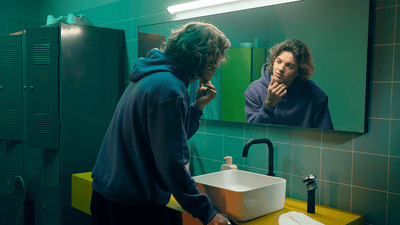 Mężczyzna patrzący w lustro, delikatnie dotykając twarzy