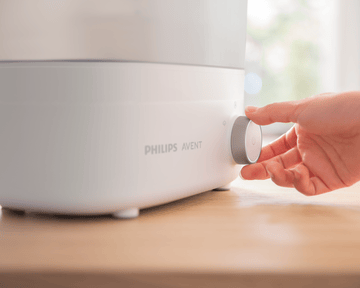 Close-up of hand using bottle sterilizer