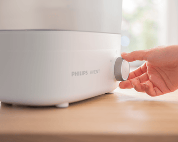 Primer plano de una mano usando el esterilizador de biberones