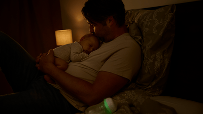 Baby napping on parent’s chest with content smile