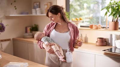 Mama trzymająca dziecko i korzystająca z laktatora Philips Avent Hands Free