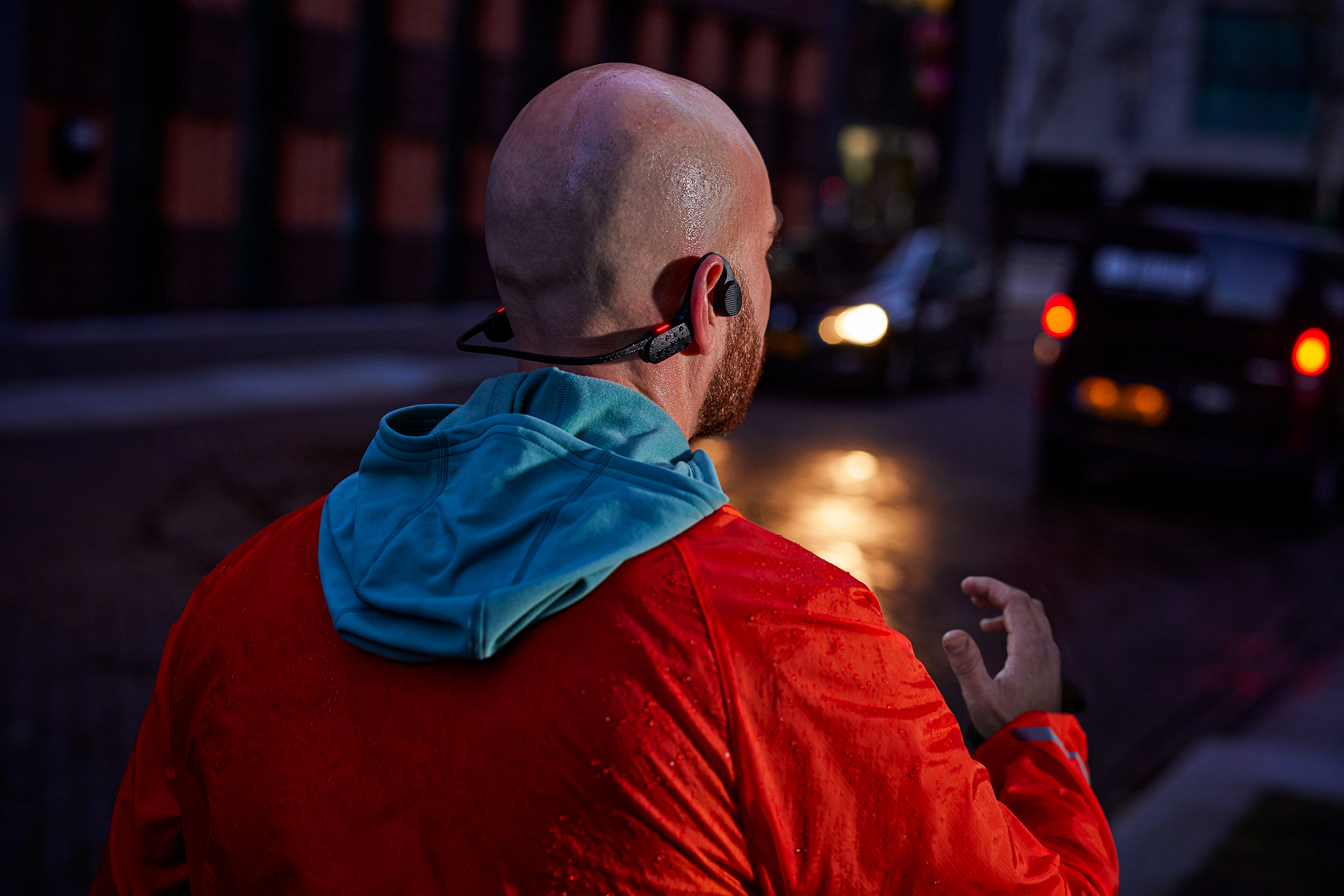 Bežec nosí športové slúchadlá Philips počas večerného behu, navrhnuté pre výk