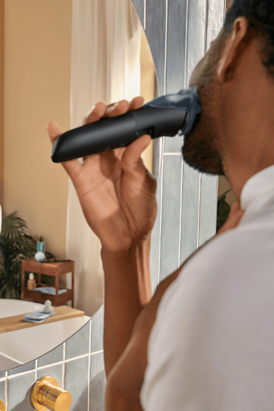 Homem a aparar a barba em frente ao espelho