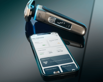 An electric shaver and a phone lying on a table
