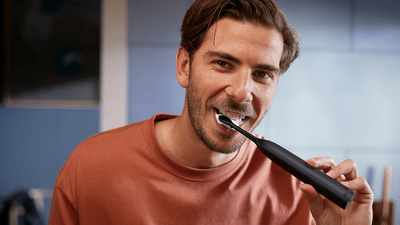 Чоловік чистить зуби та посміхається