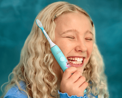 Lachend meisje met een elektrische Sonicare For Kids-tandenborstel.