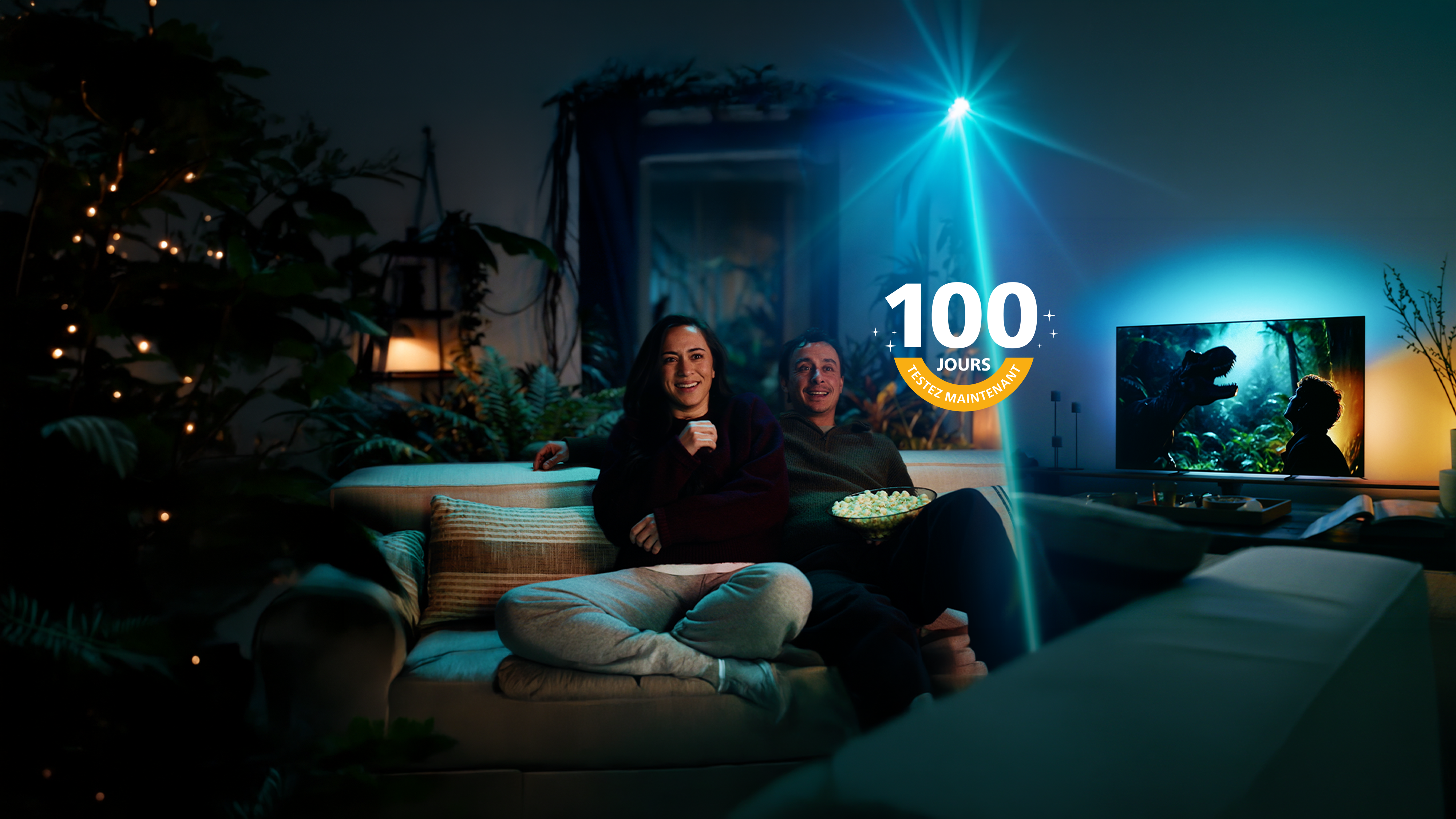 Deux personnes sont assises sur un canapé et regardent un téléviseur Philips Ambilight, dont l’éclairage d’ambiance prolonge l’expérience du film dans toute la pièce.