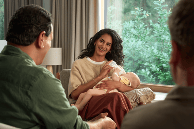 Picture of a woman feeding a baby with a sterilised baby bottle sitting on a comfortable chair.