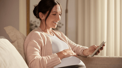 Бременна жена релаксира на дивана с книга