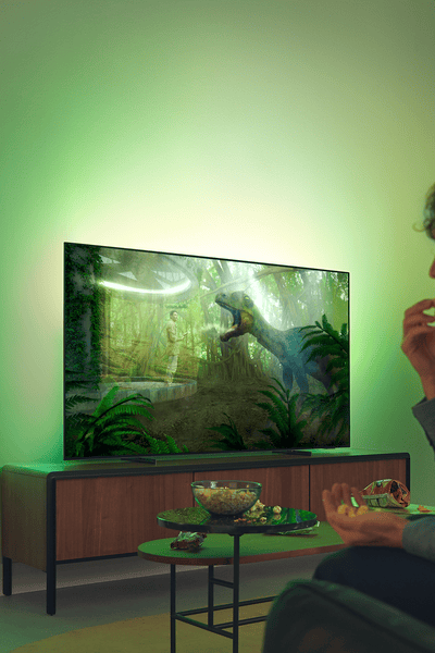 Philips Ambilight TV in a living room with two people watching.
