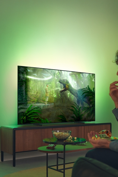 Philips Ambilight TV in a living room with two people watching.
