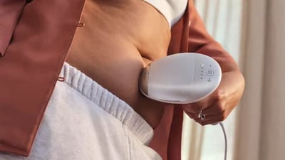A close-up of a woman using the Philips Lumea 9900 Pro IPL device on her stomach hair.