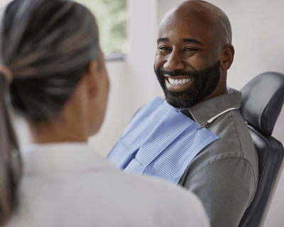 A paitent in a dental chair smiling at a dental professional.