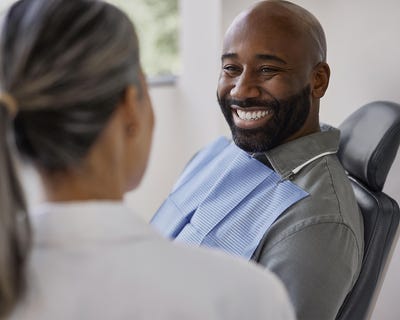 A paitent in a dental chair smiling at a dental professional.