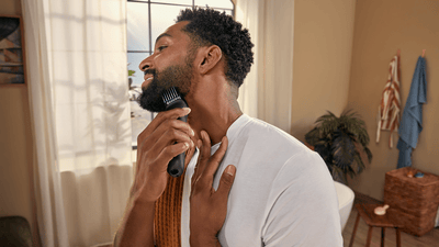 A man is shaping and trimming his three-day beard using a Philips beard trimmer.