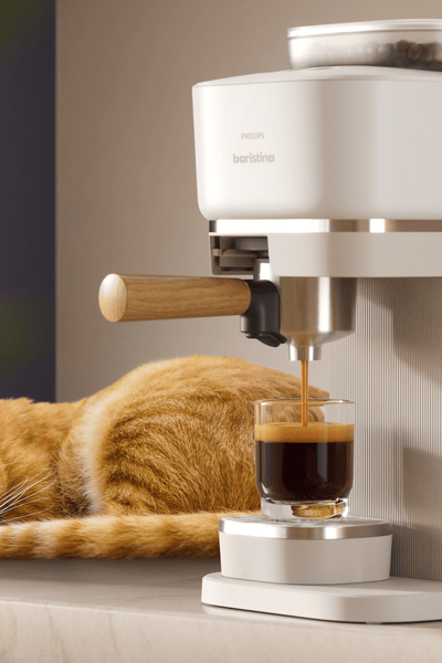 آلة Baristina من Philips وبجوارها قطة نائمة