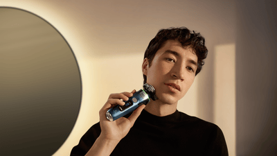Ein Mann rasiert seinen Kinnbereich mit einem blauen Philips-Rasierer.