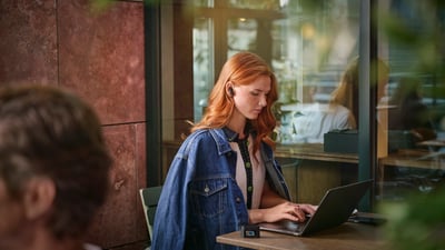 Kobieta nosząca nauszne słuchawki Philips z funkcją redukcji hałasu w głośnym pomieszczeniu.