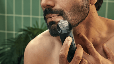 Close-upfoto van een man die een Philips baardtrimmer gebruikt om zijn walrussnor in model te brengen.