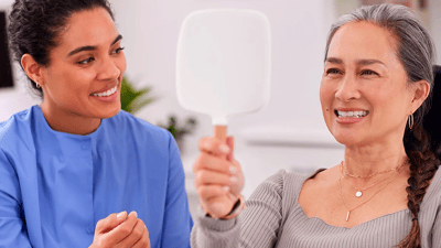 Dentist with patient looking into mirror.