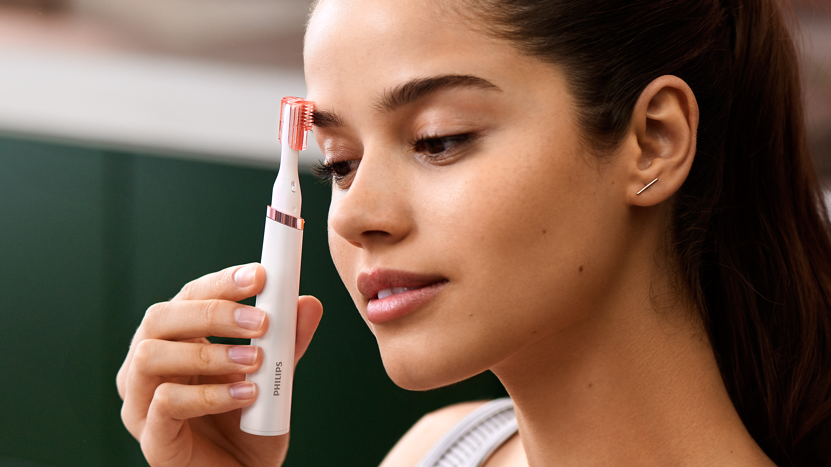 A woman using a Philips pen trimmer on her eyebrows.