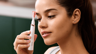 A woman using a Philips pen trimmer on her eyebrows.