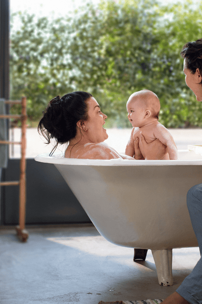 A baby in the bath with two women