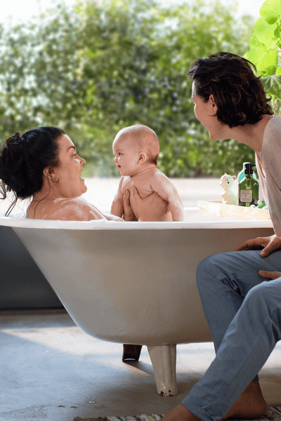A baby in the bath with two women