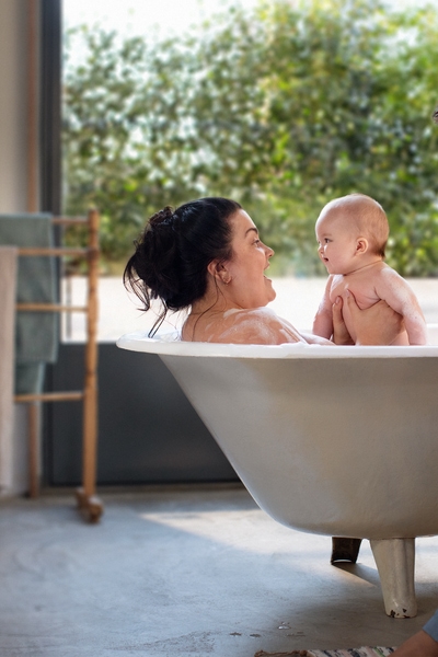 Baby smiling in a bath with two women