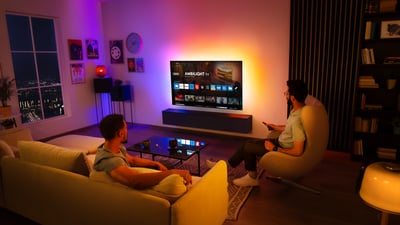 Dva muškarca gledaju Ambilight televizor postavljen na zid u dnevnoj sobi