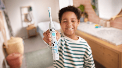 Un bambino mostra alla telecamera il suo spazzolino elettrico Philips.
