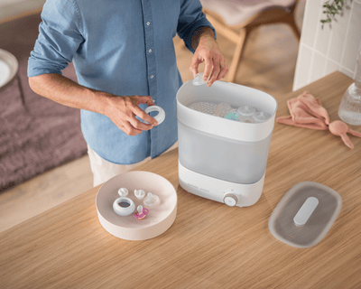 Man putting bottles and pacifiers into the sterilizer