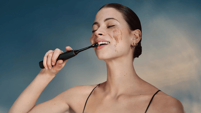 Жінка чистить зуби звуковою зубною щіткою