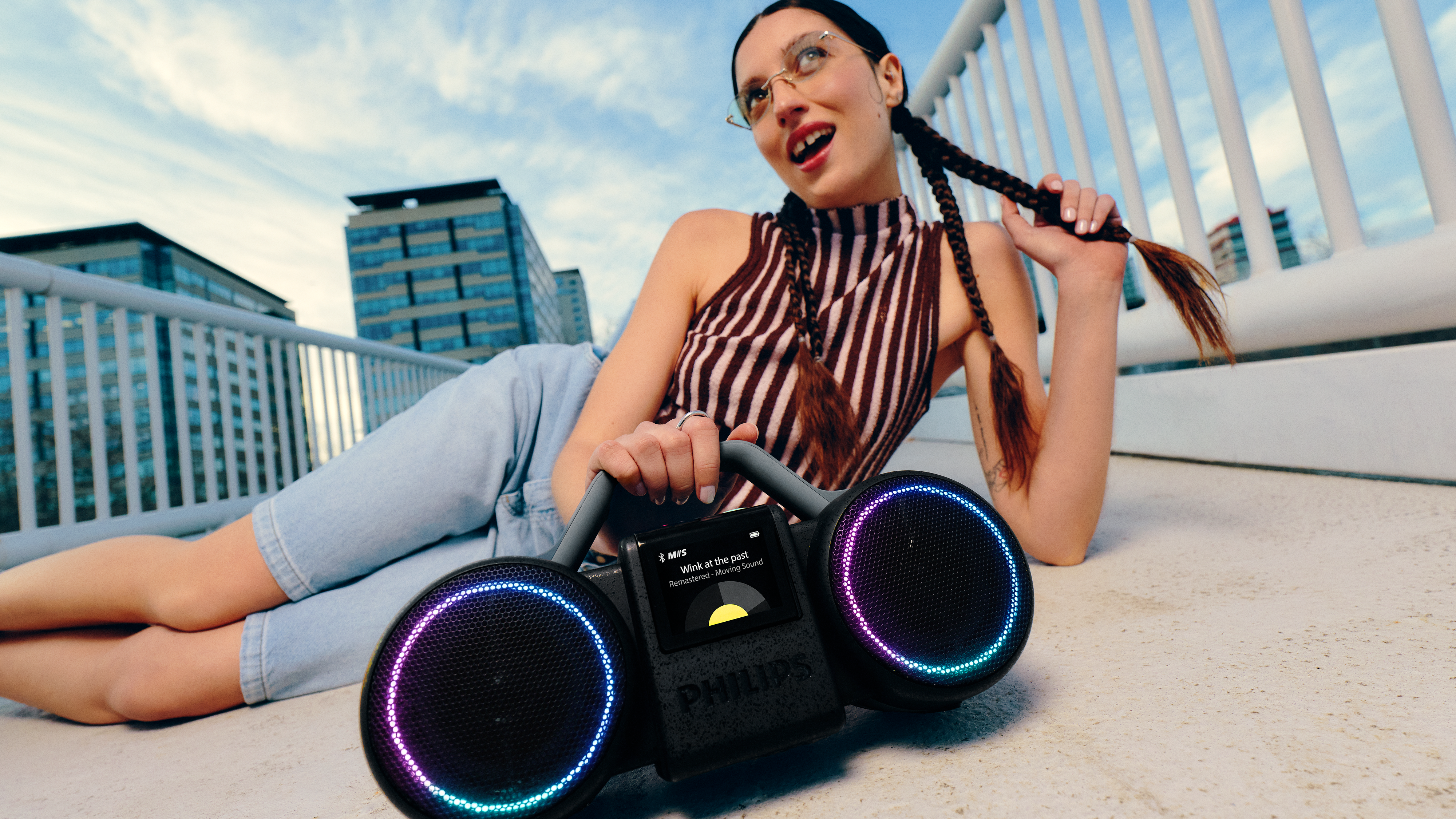 Eine Frau sitzt mit einer Boombox auf dem Boden und hört Musik. Das Bild vermittelt eine entspannte ...