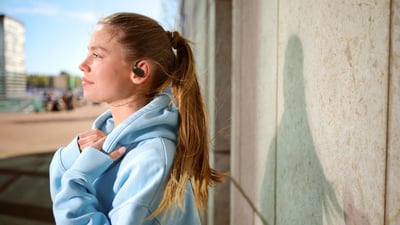 Kobieta nosząca prawdziwie bezprzewodowe słuchawki douszne Philips podczas relaksu na świeżym powietrzu, ciesząca się czystym dźwiękiem i komfortem.