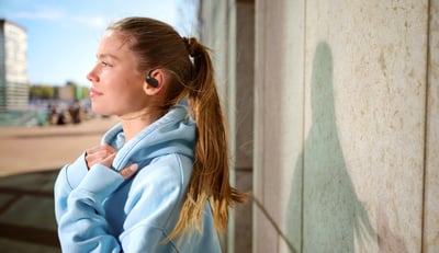 Vrouw die Philips true wireless oordopjes draagt terwijl ze buiten ontspant en geniet van helder geluid en comfort