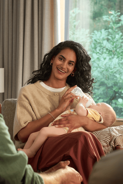 Mom feeding baby with warm sterilized bottle