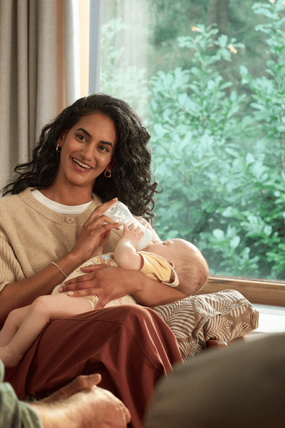 Maminka krmí dítě teplou sterilizovanou lahví